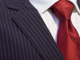 عکس یک کراوات شیک و زیبای قرمز رنگ که به خوبی گره خورده است و با یک کت و شلوار شیک ست شده است